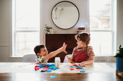 Young brother showing sister messy hands with doing a craft