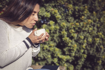 Disconnecting, latina woman taking a break with coffee in the garden