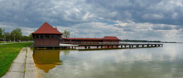 House by lake against sky