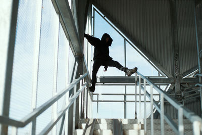 Low angle view of man jumping on staircase of building