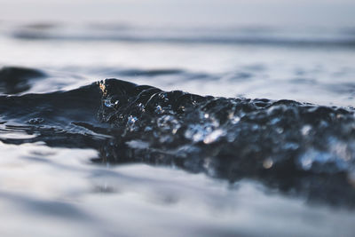 Close-up of water flowing over sea against sky