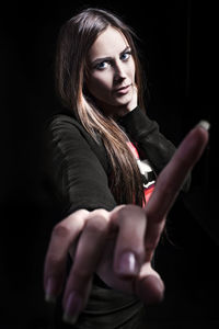 Close-up of young woman against black background