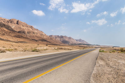 Road leading towards mountains against sky