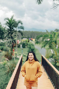 Portrait of smiling young woman standing against trees