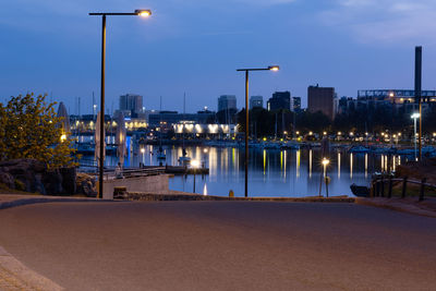 View of a shore promenade with a calm sea and sleeping city in the background.