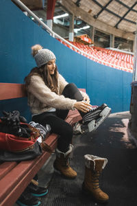 Full length of woman wearing skate while sitting on bench