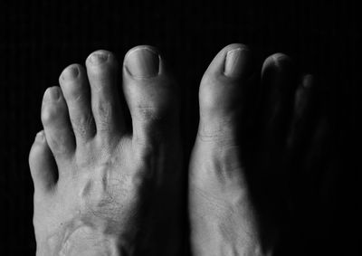Low section of bare feet against black background