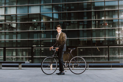 Man riding bicycle on building in city