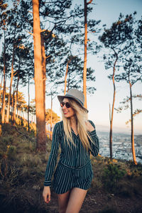 Woman standing against trees during sunset