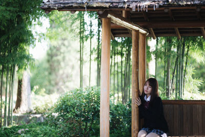 Portrait of woman sitting against trees