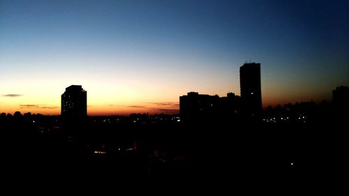 Illuminated cityscape against sky at sunset