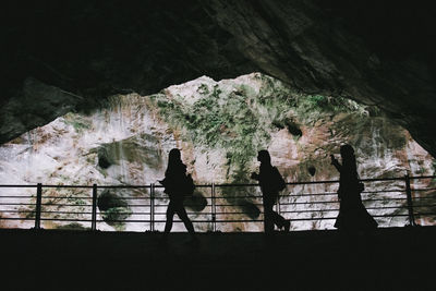 Silhouette people standing on rock