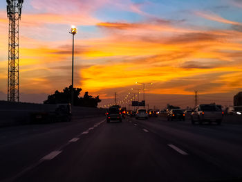 Cars on road against sky during sunset