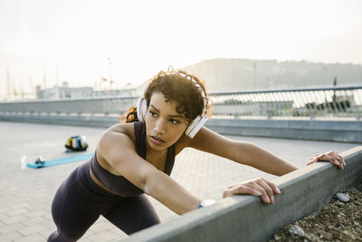 Sportswoman with headphones exercising on bridge