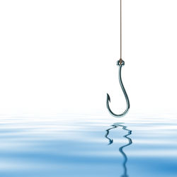 Close-up of water drop hanging on metal against wall