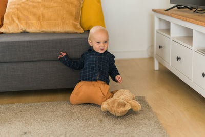 Portrait of cute baby girl sitting on sofa at home