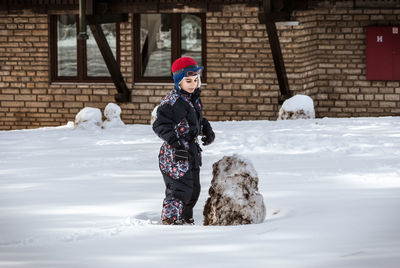 Boy playing on snow covered yard during winter