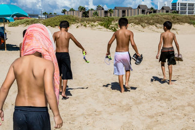 Rear view of shirtless men on beach