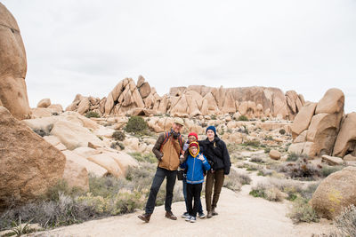 Family of four having fun surrounded by rocks and shrubs in desert