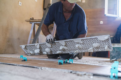 Mature man putting parquet floor in house