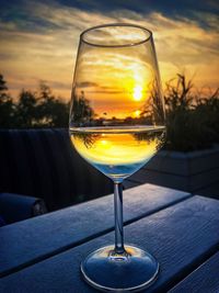 Close-up of wineglass on table against sky during sunset