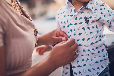 Mom buttoning baby boy's shirt, close up to hands