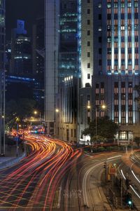 Light trails on city street by buildings at night