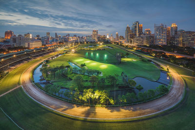 Aerial view of illuminated city by buildings against sky