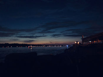 Silhouette of illuminated beach against sky at night