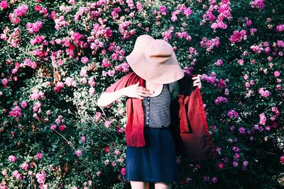 Woman standing by pink flowering plants