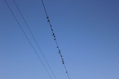 Low angle view of power lines against clear blue sky