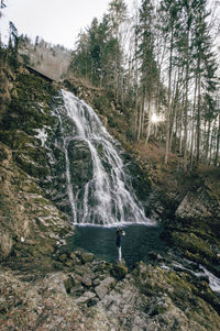 High angle view of person standing on mountain by waterfall