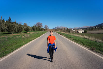 Portrait of man riding motorcycle on road against blue sky