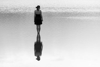 Rear view of woman standing on water with reflection