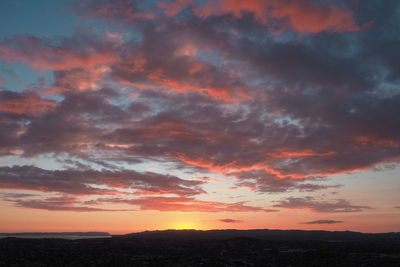 Low angle view of dramatic sky over silhouette landscape