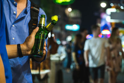 Midsection of man holding wine bottles