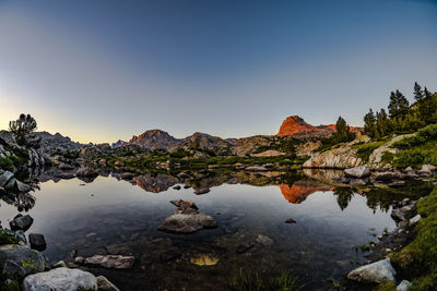 Reflection of rocks in lake against clear sky