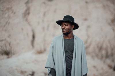 Young man looking away while standing outdoors