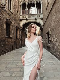 Portrait of young woman standing against building