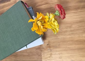 High angle view of yellow flowers and book on table