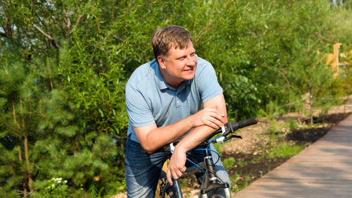 Portrait of an adult male blond 40-44 years old with a wide smile sitting on bicycle.