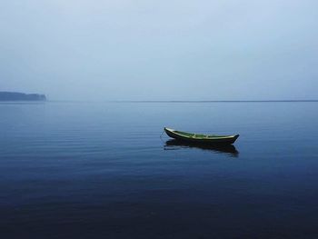 Boat moored in lake against sky during foggy weather