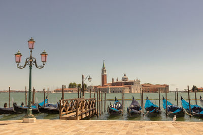 Gondola moored on canal against clear sky in venice