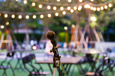 Microphone at party against illuminated light bulbs at dusk