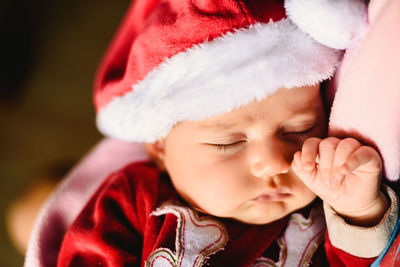 High angle view of cute baby girl sleeping while wearing santa claus costume