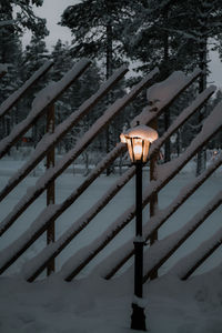 Illuminated street light against railing in winter