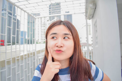 Portrait of young woman standing against building