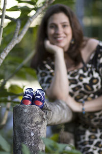 Baby booties on wooden railing with happy pregnant woman in background