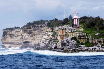 Lighthouse by sea against sky