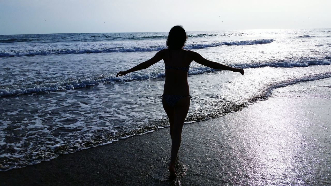 sea, water, horizon over water, full length, leisure activity, silhouette, lifestyles, standing, beach, shore, tranquility, tranquil scene, rear view, nature, scenics, sky, beauty in nature, wave